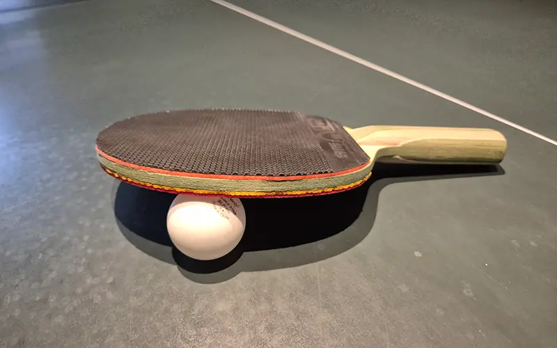 Tischtennisschläger mit Ball Tischtennisschläger mit Ball auf einer Tischtennisplatte